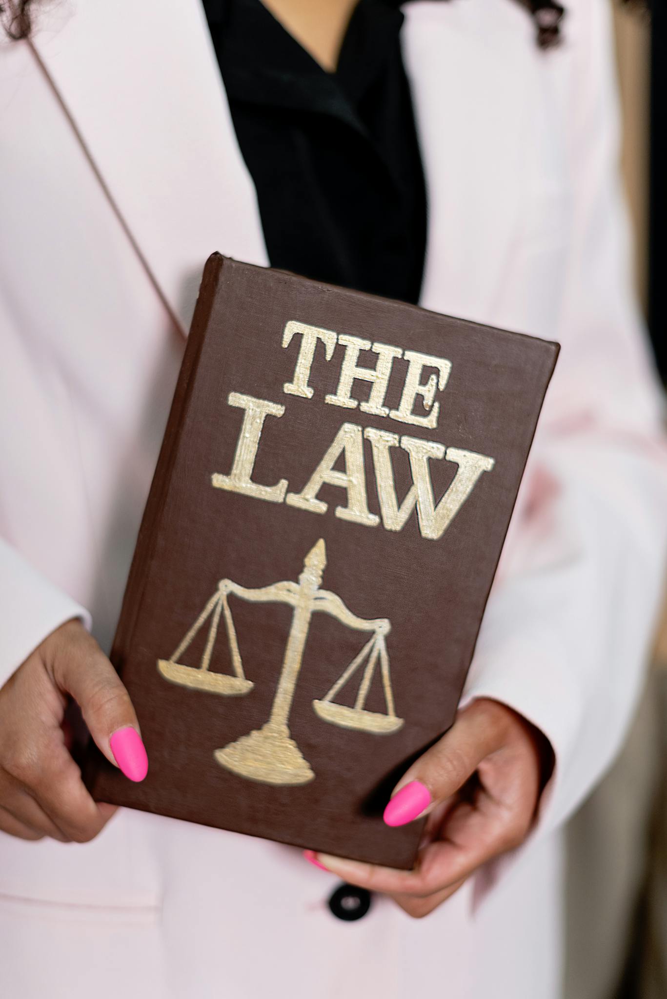 Close-up of a woman holding a law book with scales of justice, emphasizing legal themes.