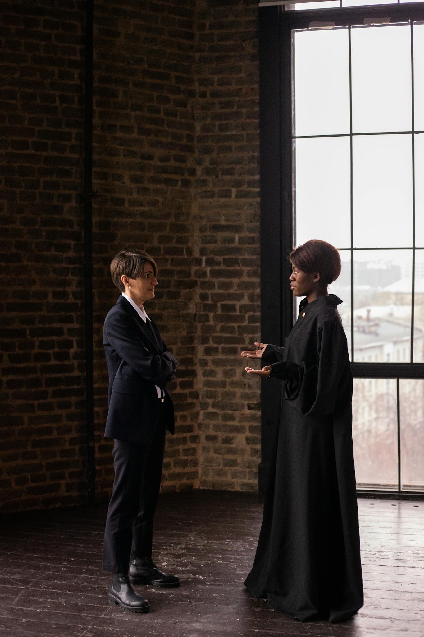 Two professionals engaging in a legal discussion by a large window in a courtroom setting.